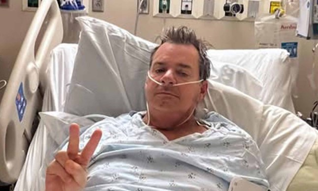 Rock star David Roach of Junkyard poses in his hospital bed for a photo