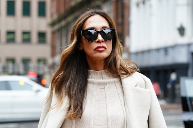 Myleene Klass arriving at Birmingham Crown Court in a cream trench coat over jumper and trousers. She is wearing sunglasses