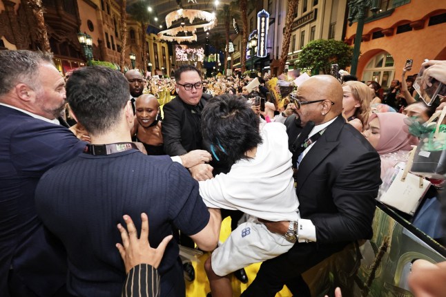 This picture by The Straits Times taken November 13, 2025 and provided on November 14 shows a man (C) accused of attacking pop star Ariana Grande being grabbed by security guards as co-star Cynthia Erivo (3rd L) reacts at the premiere of their film "Wicked: For Good" in Singapore. Singapore authorities charged an Australian man November 14 for rushing pop diva Ariana Grande at the Asia premiere of her latest movie, as outraged fans called for the alleged serial intruder "to be dealt with". (Photo by The Straits Times / AFP) / - Singapore OUT / -----EDITORS NOTE --- RESTRICTED TO EDITORIAL USE - MANDATORY CREDIT "AFP PHOTO / THE STRAITS TIMES - NO MARKETING - NO ADVERTISING CAMPAIGNS - DISTRIBUTED AS A SERVICE TO CLIENTS - NO ARCHIVES (Photo by STR/The Straits Times/AFP via Getty Images)